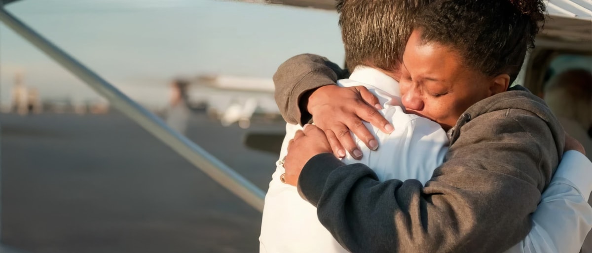 Judah 1 pilot and passenger embrace beside mission aircraft